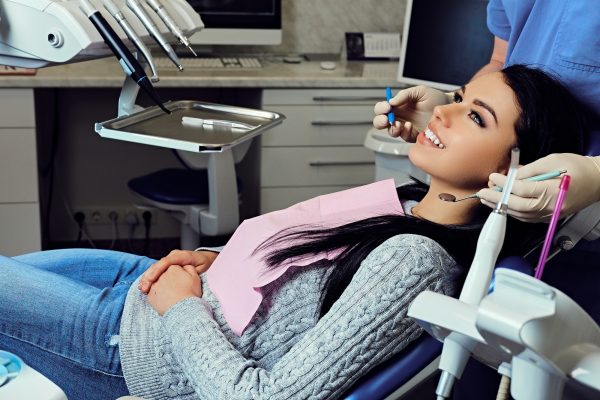 Dentist examining female's teeth in dentistry.